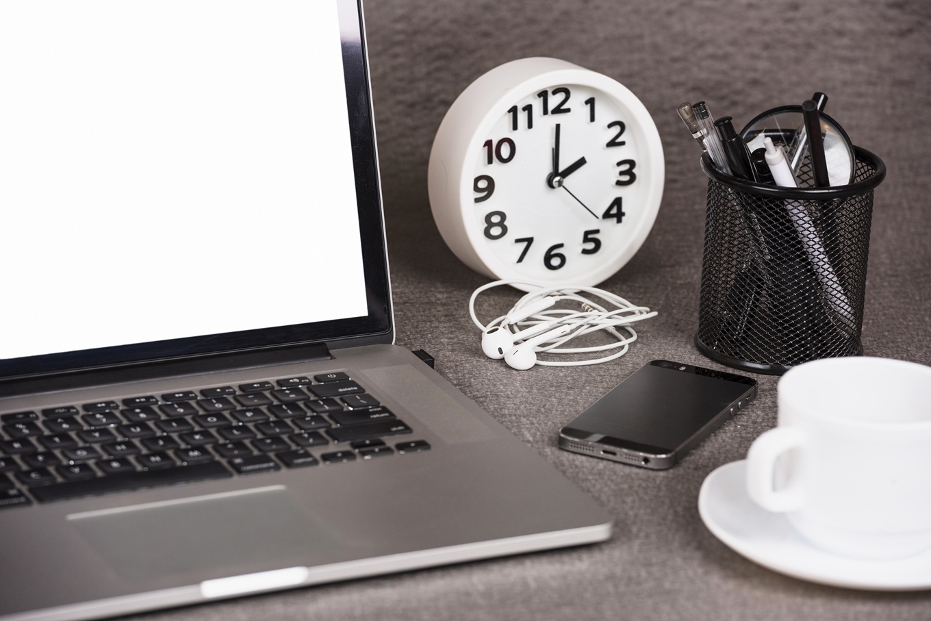 Escritorio con ordenador portátil, reloj y material de oficina